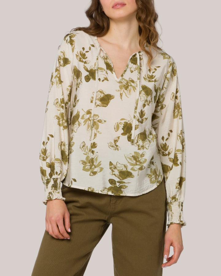 Woman wearing a floral blouse and brown pants on a white background
