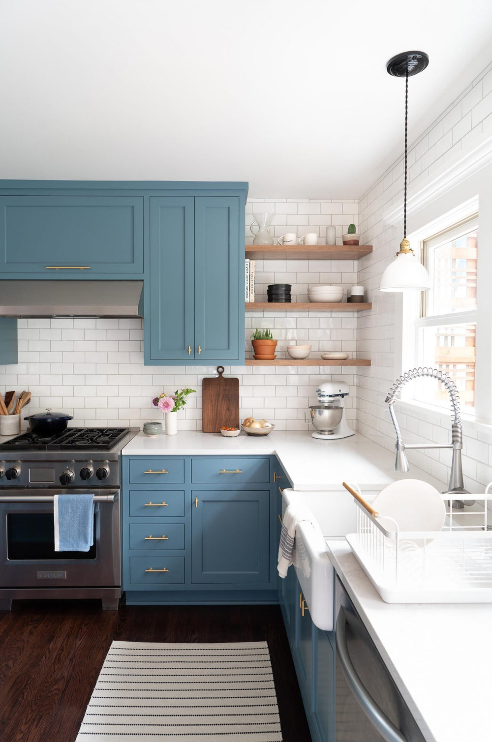 Modern kitchen with blue cabinets, white countertops, and stainless steel appliances.