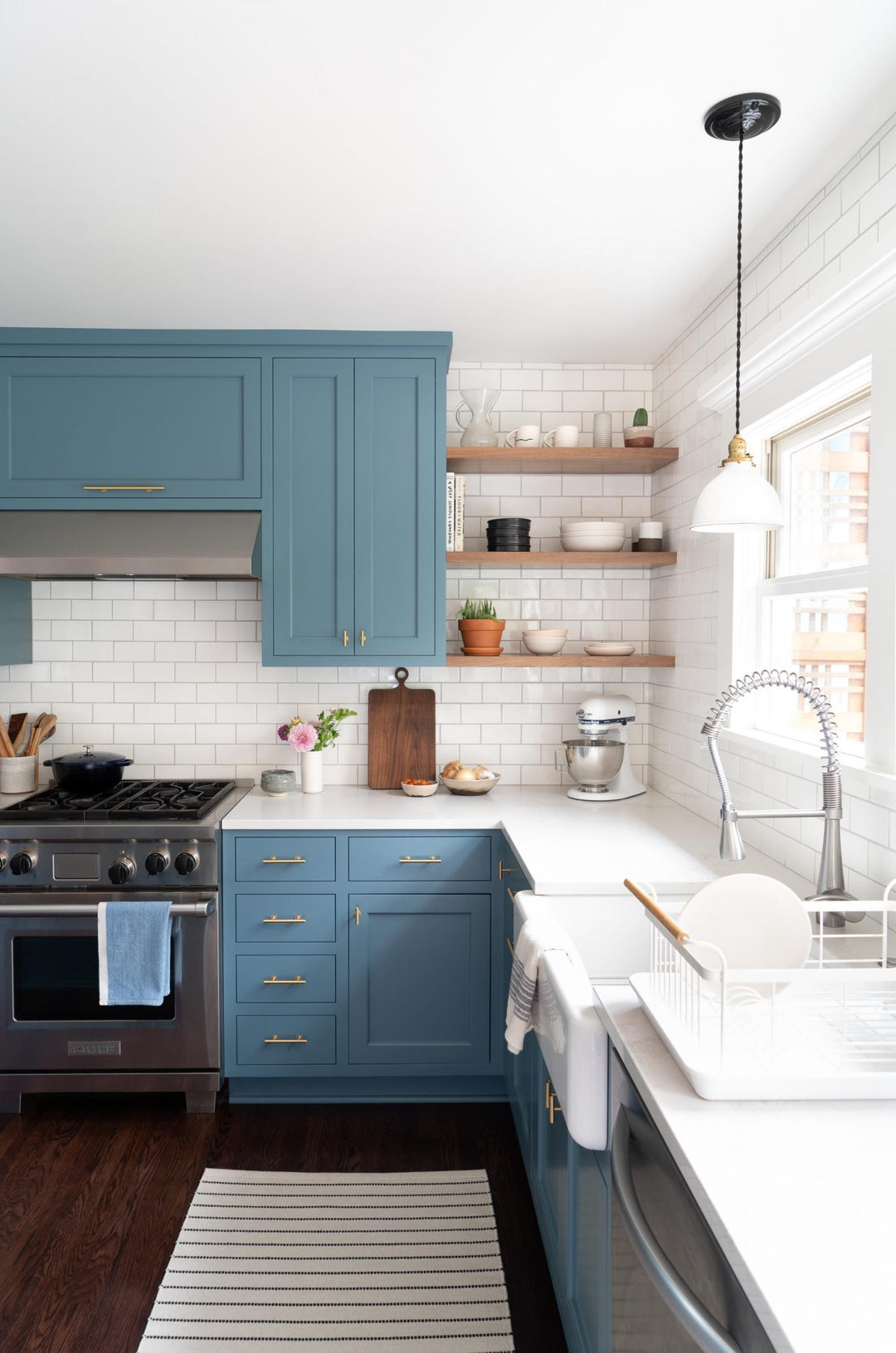 Modern kitchen with blue cabinets, white countertops, and stainless steel appliances.