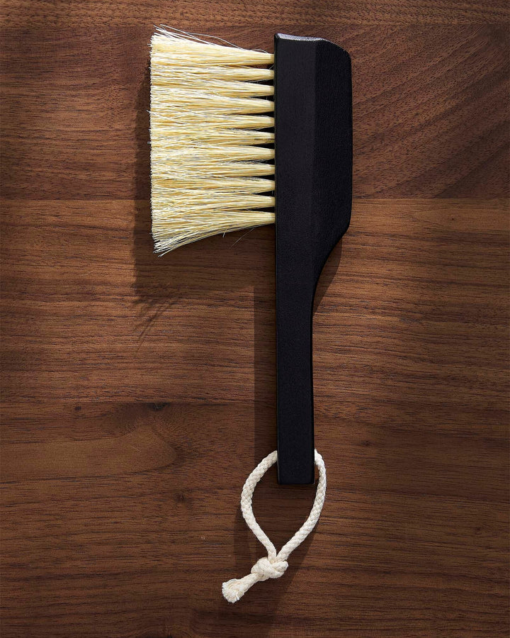 Black brush with white bristles on a wooden surface