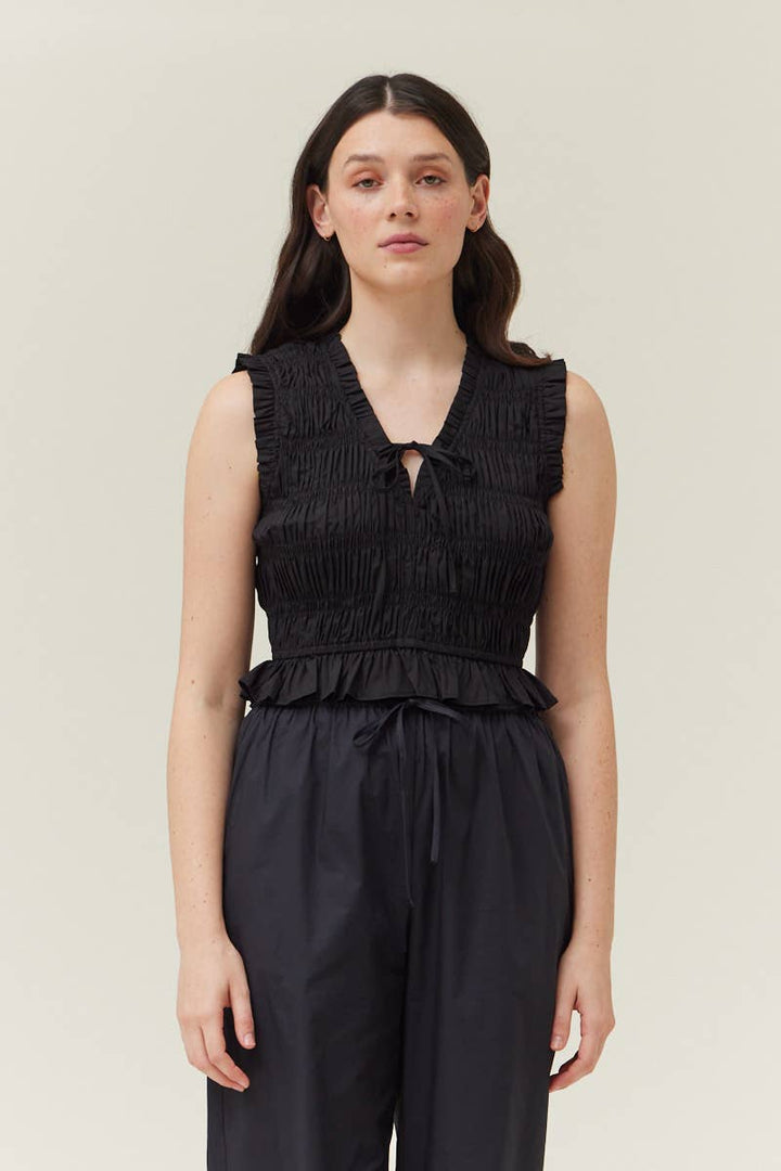Woman wearing a black smocked sleeveless top sold at shopwinsome.com a cute boutique based in chicago il