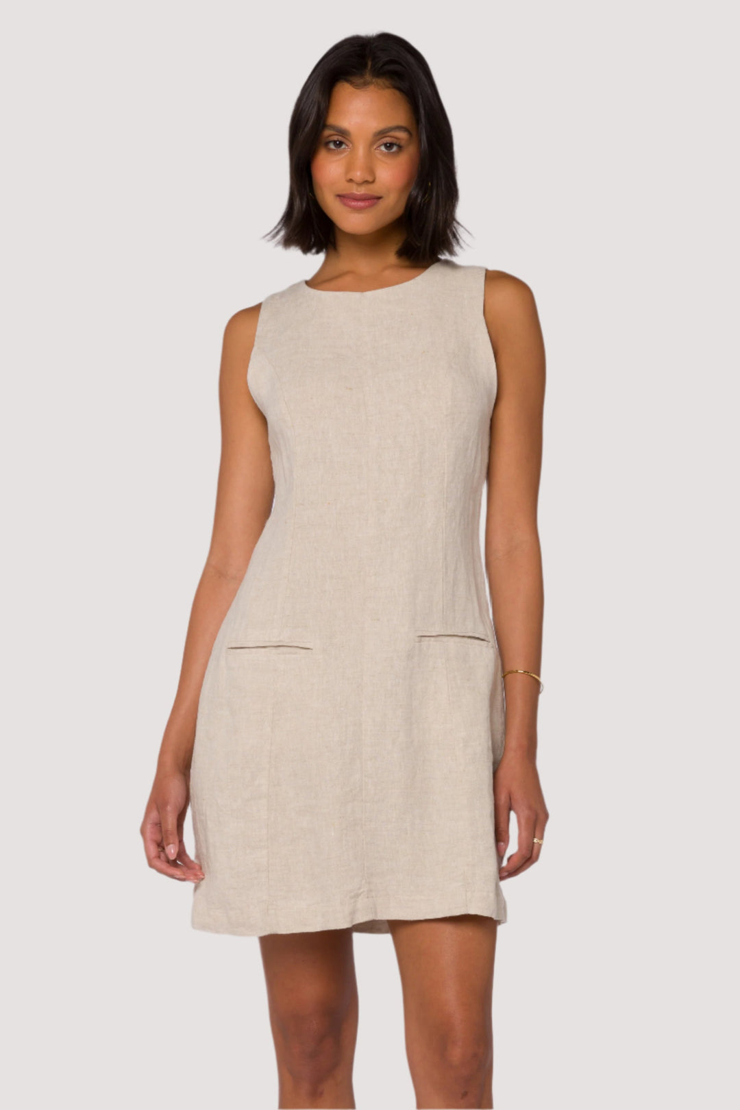 Woman wearing a beige sleeveless linen dress on a white background
