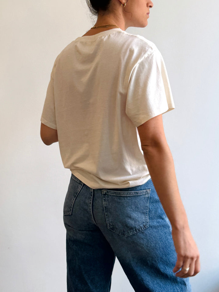 Person wearing a plain white t-shirt and blue jeans against a light background