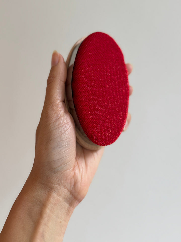 Hand holding a red lint remover against a plain background