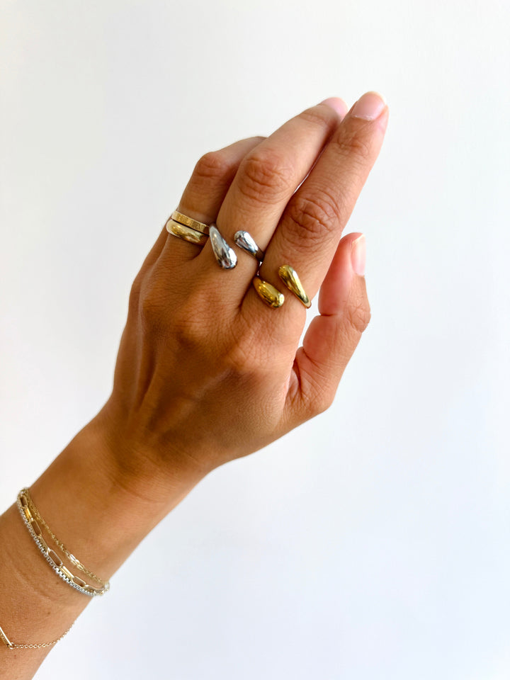 Hand wearing multiple gold and silver rings on a white background