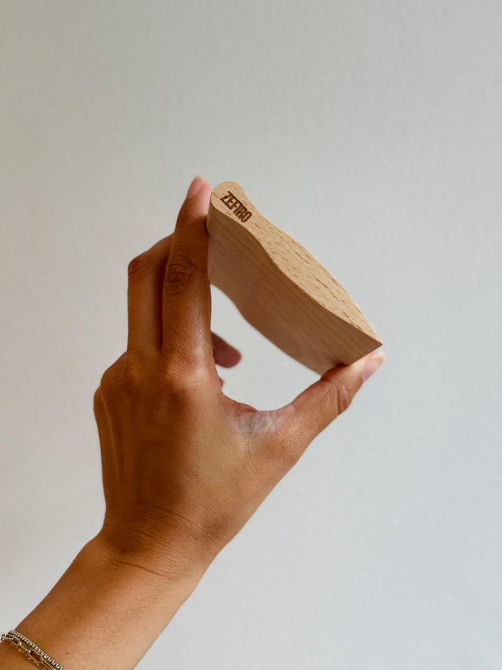 Hand holding a wooden kitchen scraper knife with 'ZEFIRO' branding against a plain background