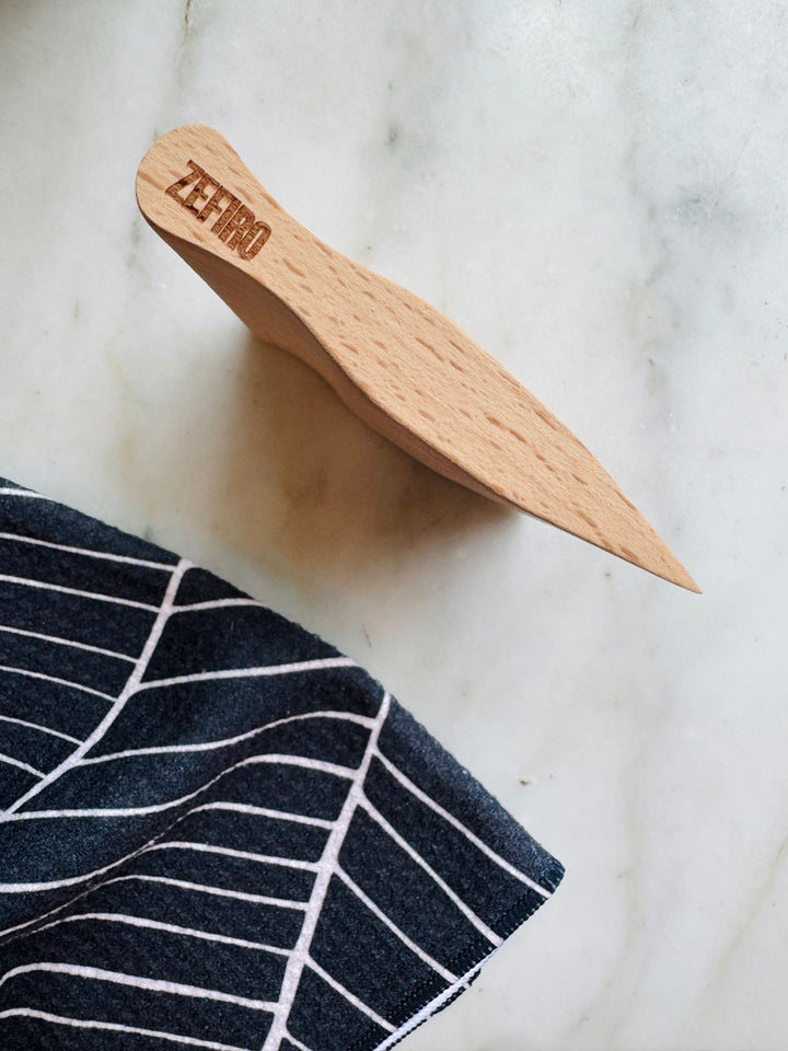 Wooden scraper with 'Zefiro' branding on a marble surface