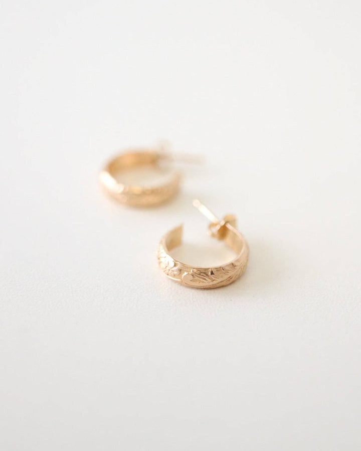 Gold hoop earrings on a light gray background