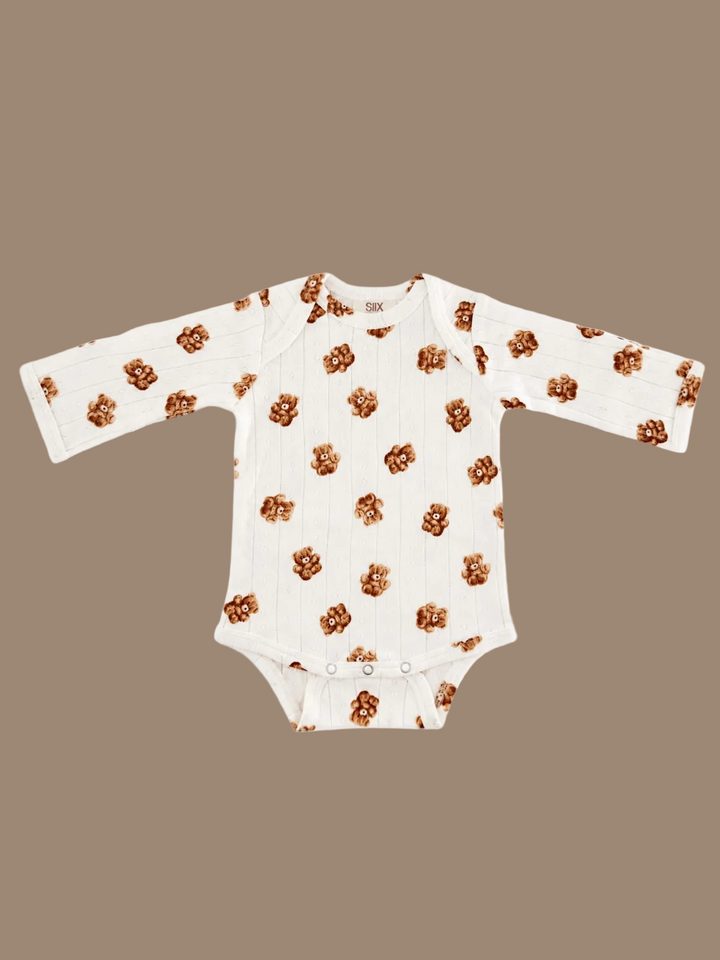 A long-sleeve baby bodysuit in off-white ribbed fabric, featuring an all-over pattern of small brown teddy bears, laid flat against a white background.