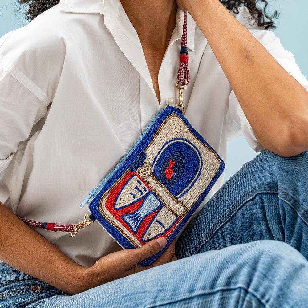 Person holding a colorful beaded purse with a blue background