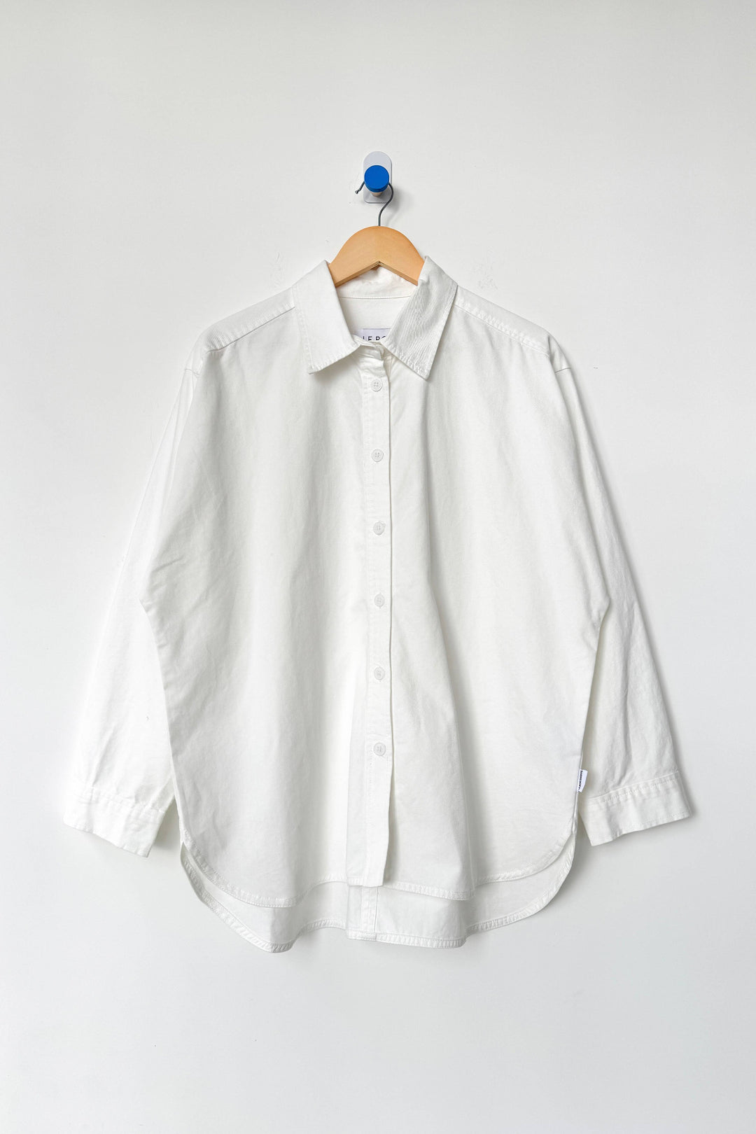 White shirt on a wooden hanger against a white background
