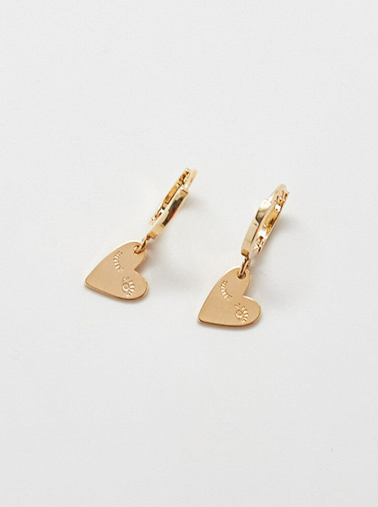A pair of gold-plated heart-shaped earrings with a wink design.