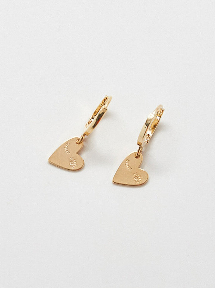 A pair of gold-plated heart-shaped earrings with a wink design.