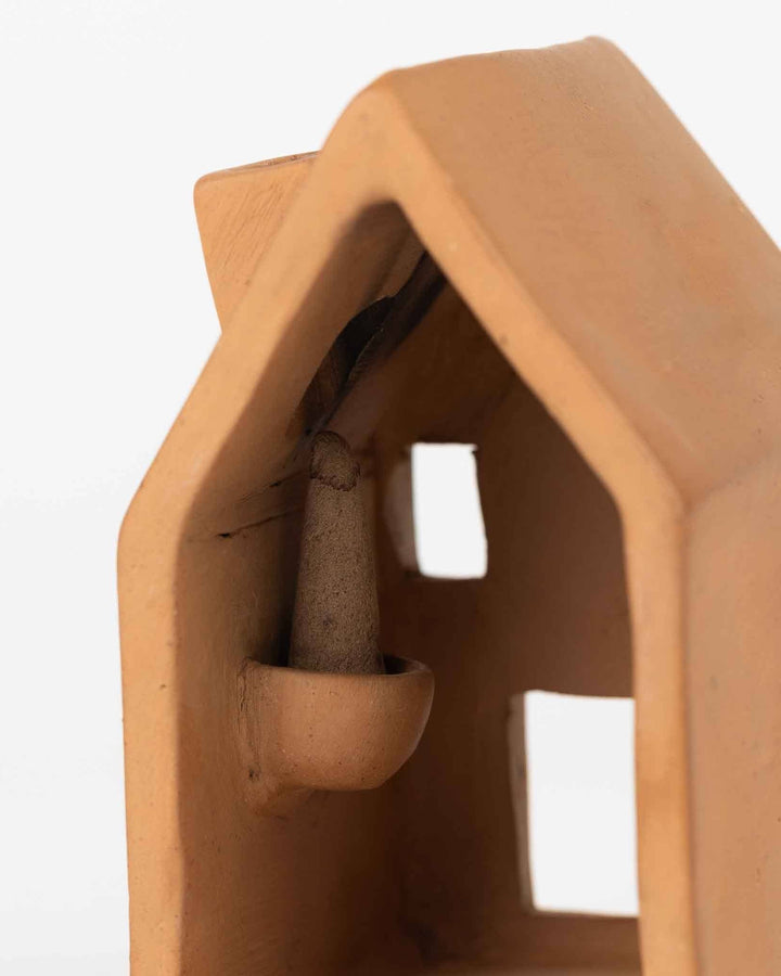 Terracotta incense holder house with a small bowl inside on a white background