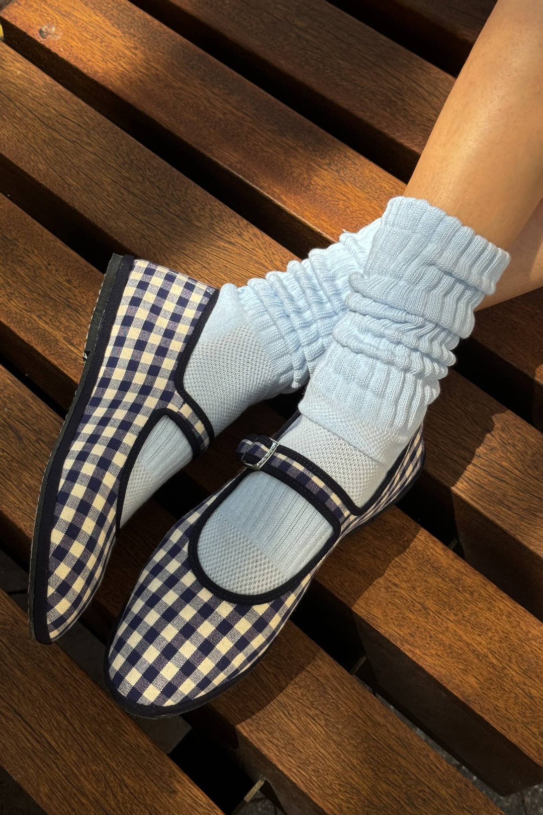 Blue checkered shoes and light blue socks on a wooden surface