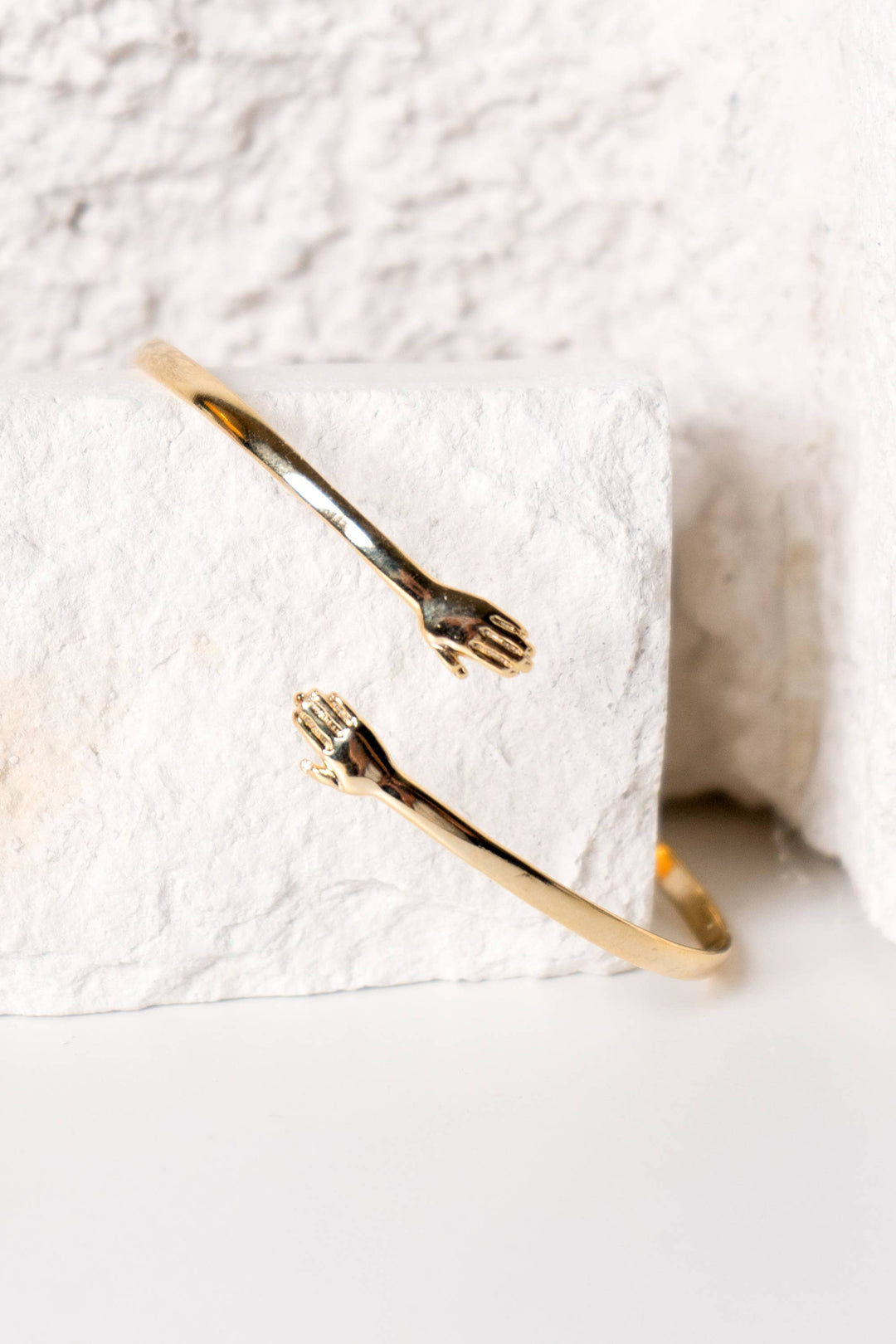 Gold bracelet with a unique hand design on a textured white surface. Winsome boutique Chicago