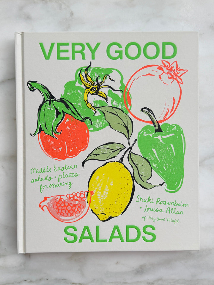 Book titled 'Very Good Salads' with illustrations of vegetables on a marble surface
