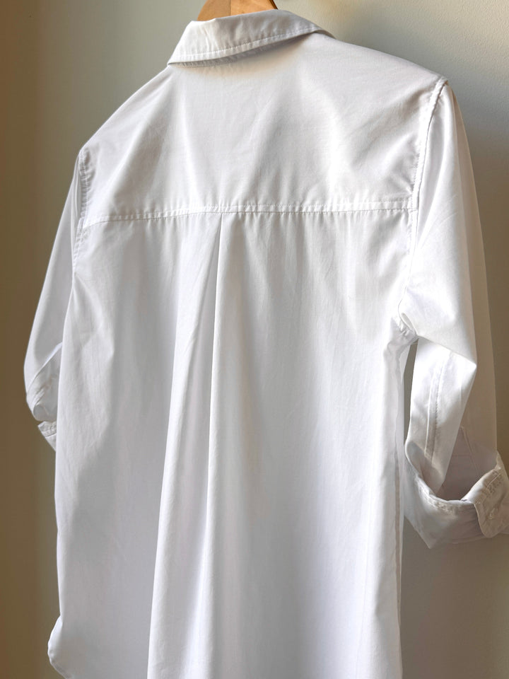 White shirt on a wooden hanger against a plain background