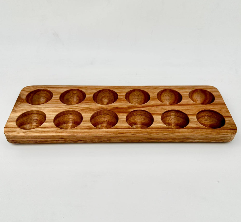 Wooden egg tray with multiple round depressions on a white background