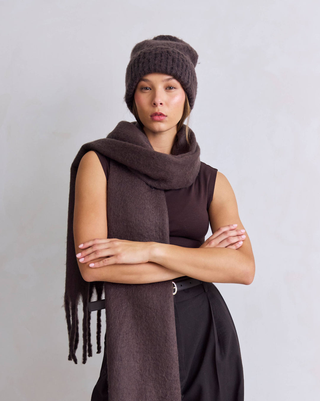 Person wearing a brown scarf and hat against a plain background