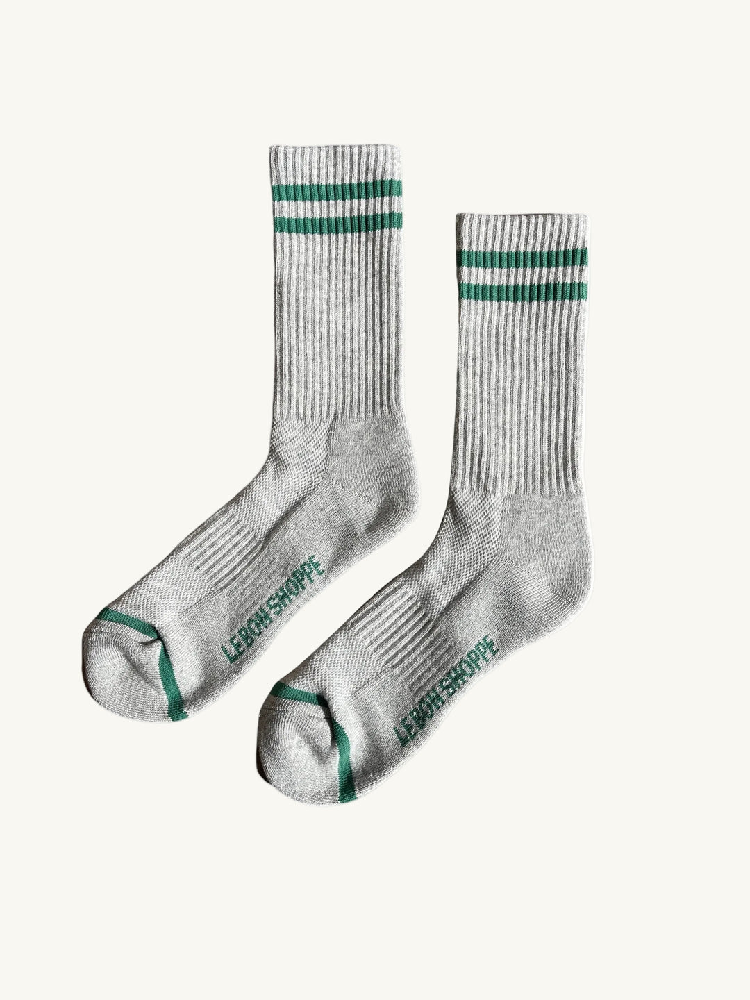 Pair of gray socks with green stripes and logo on a white background. Men's le bon shoppe socks chicago avondale winsome clothing & goods boutique