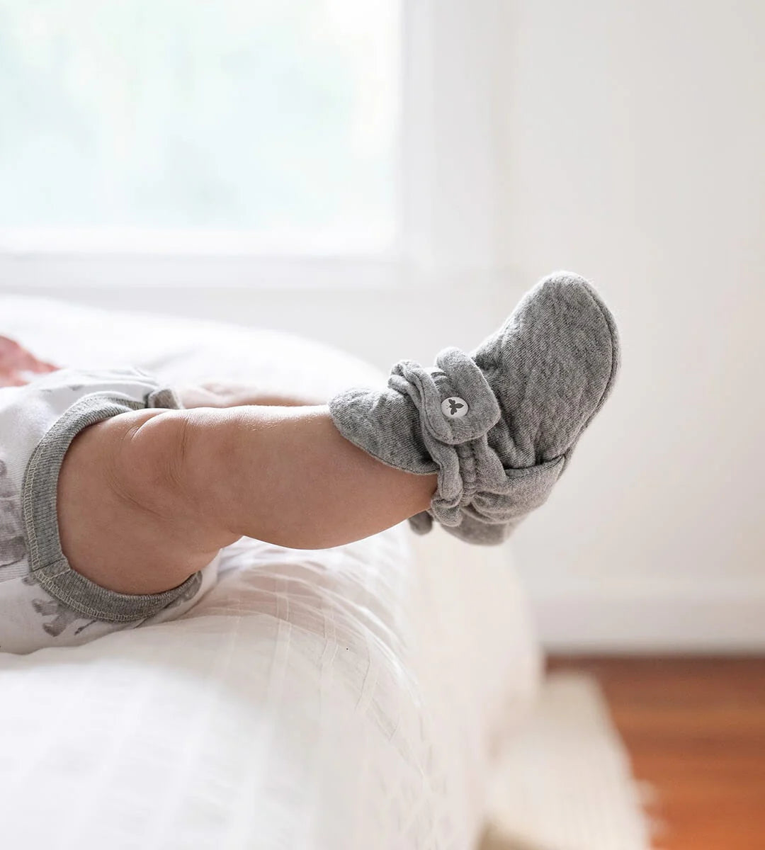 baby wearing gray booties socks on a white surface