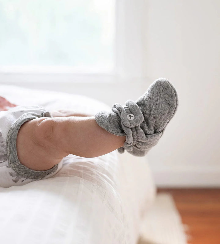 baby wearing gray booties socks on a white surface