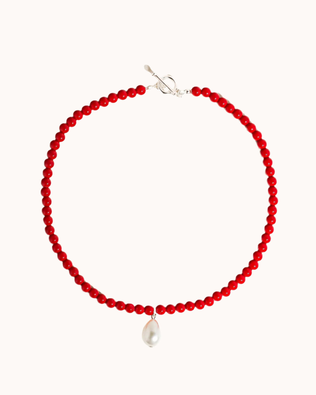 Red beaded necklace with a pearl and a silver clasp on a white background