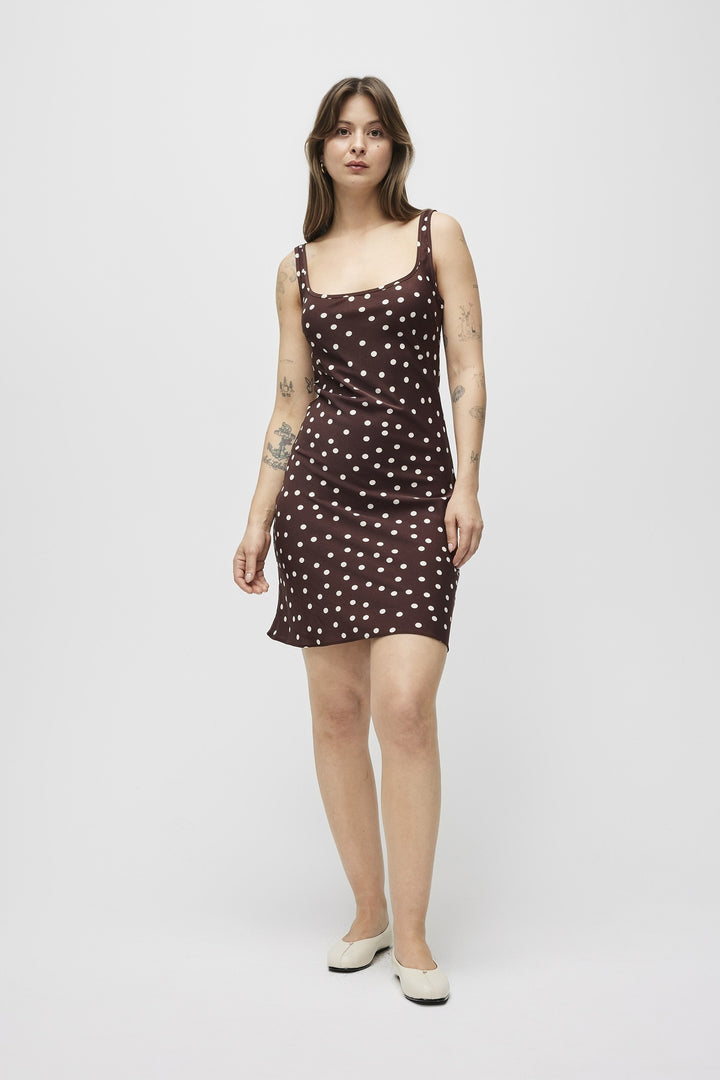 Woman wearing a brown dress with white polka dots on a white background