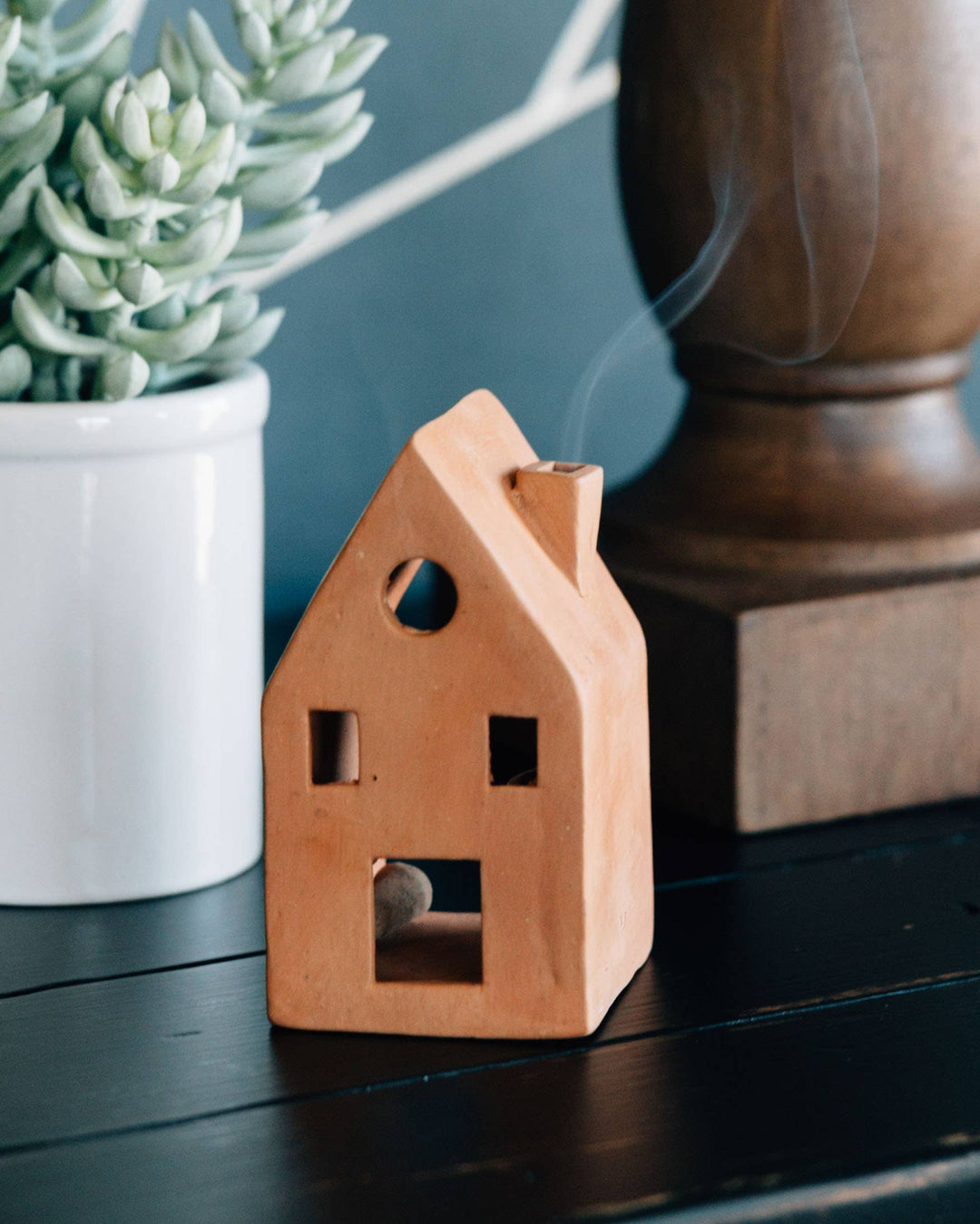 Terracotta house-shaped incense burner with smoke coming up the chimney