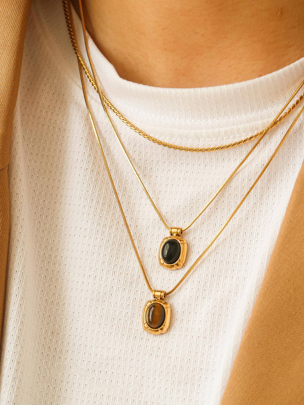 Gold necklaces with black and brown gemstones on a white background