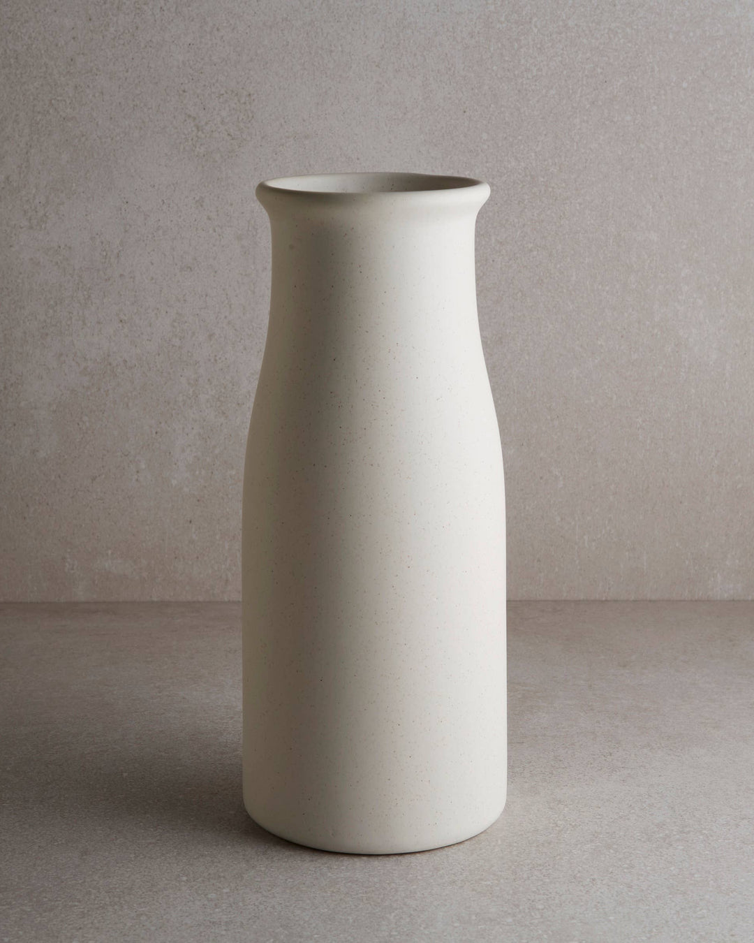 milk bottle shaped flower vase with white slightly speckled matte glaze