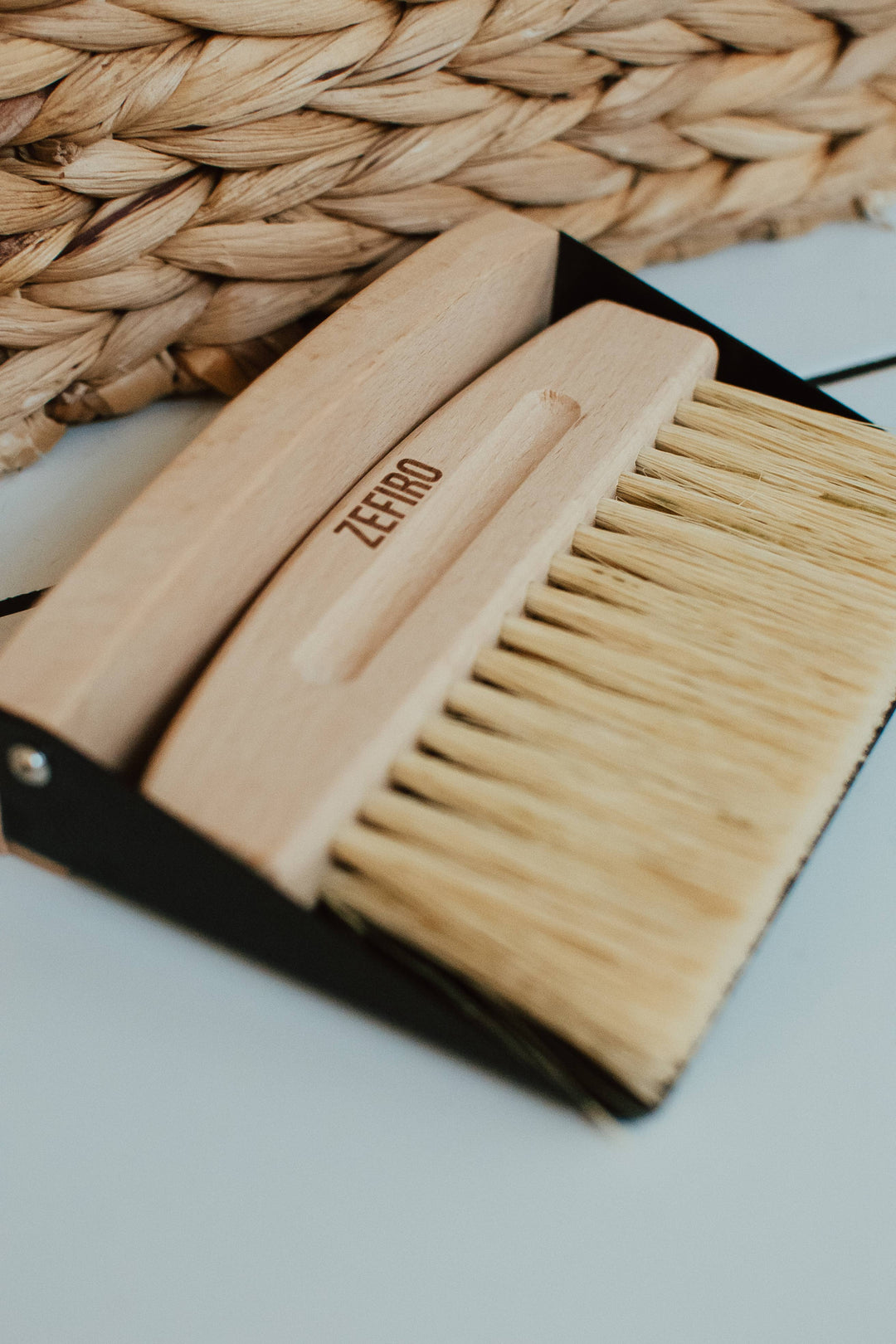 Wooden brush with black handle on a woven mat