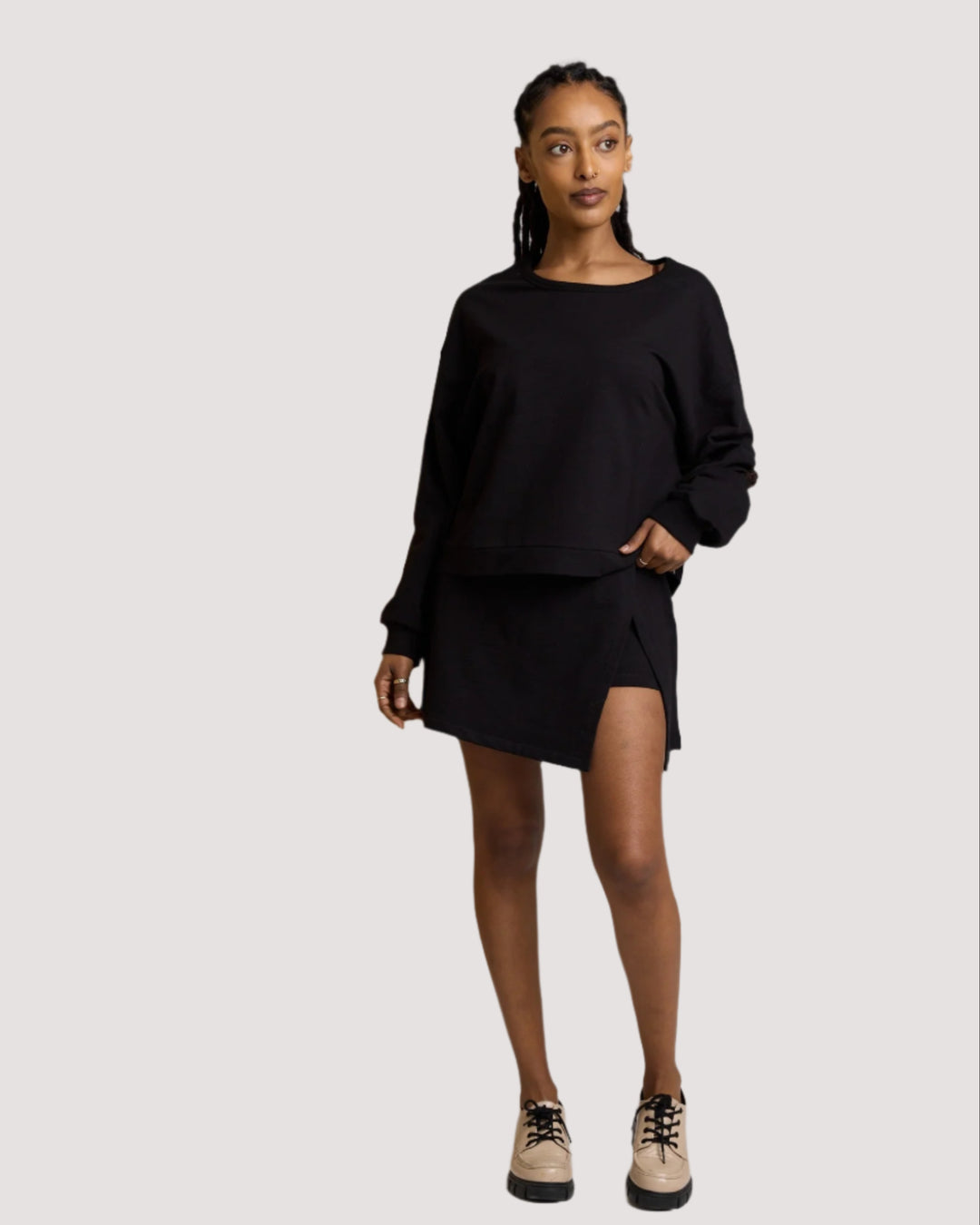 Woman wearing a black skort with beige shoes on a plain background