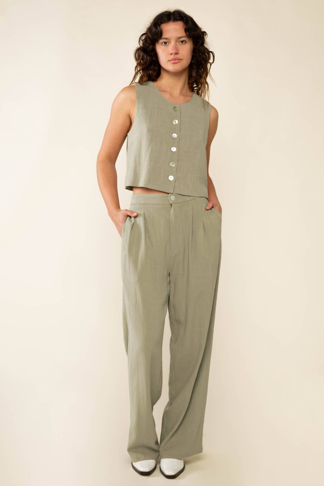 Woman wearing a green sleeveless top and pants on a beige background