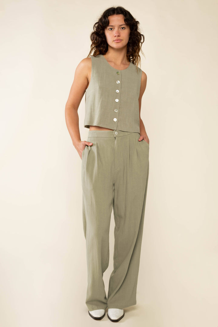 Woman wearing a green sleeveless top and pants on a beige background