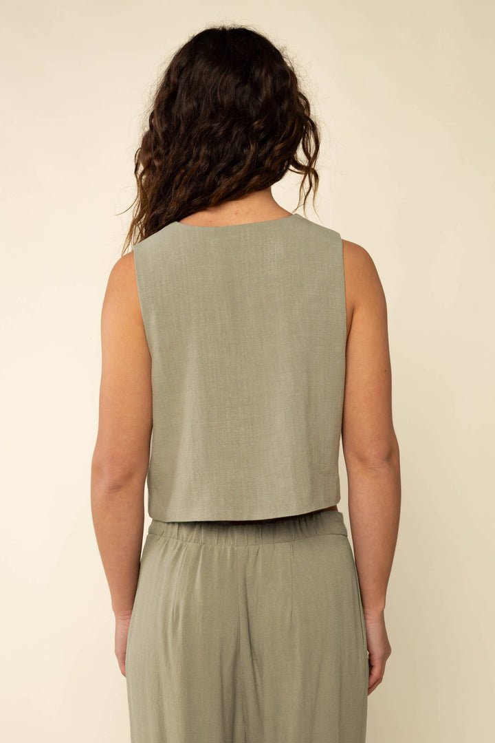 Woman wearing a sleeveless green top and matching pants against a beige background
