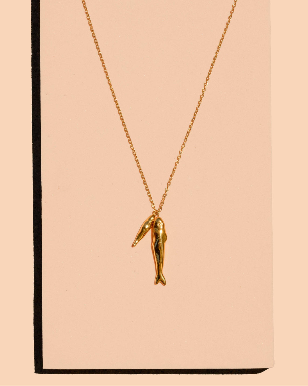 Gold necklace with a unique pendant on a beige card