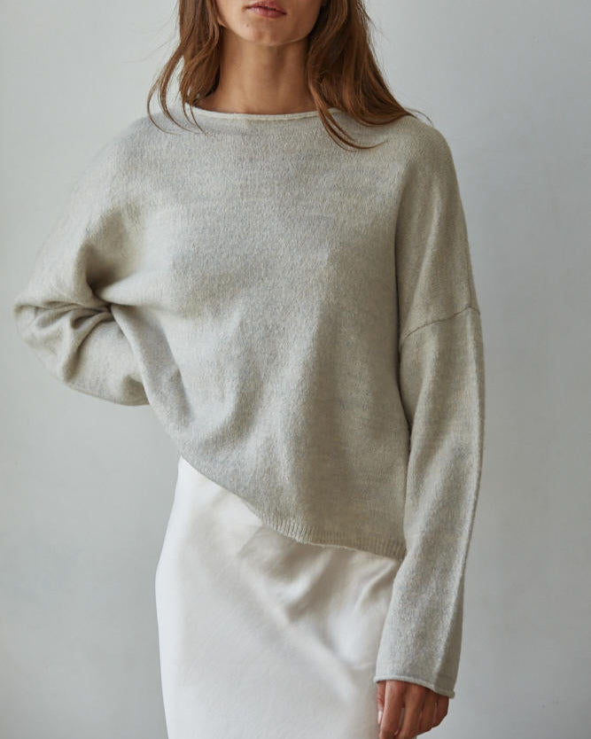 Woman wearing a light gray sweater against a plain background