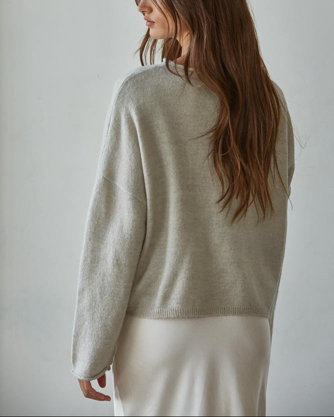 Woman wearing a beige sweater against a plain background