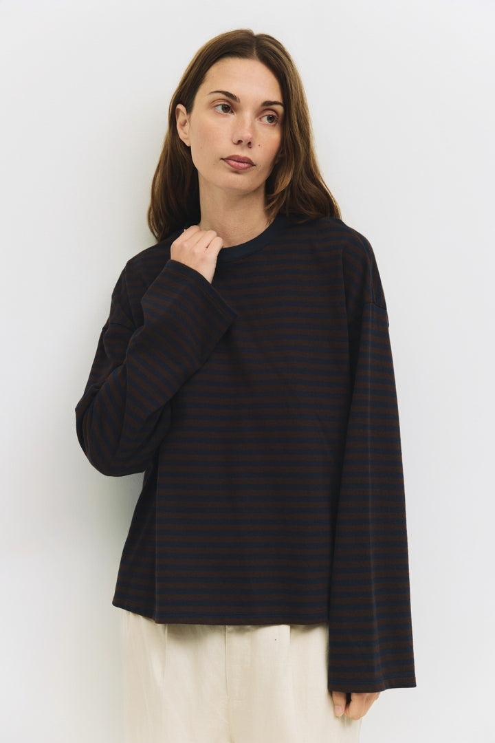 Woman wearing a brown and navy striped top against a white background