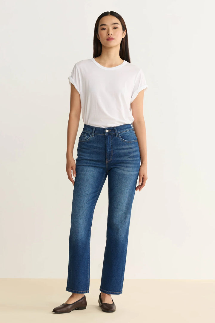 Woman wearing a white t-shirt and blue jeans on a plain background