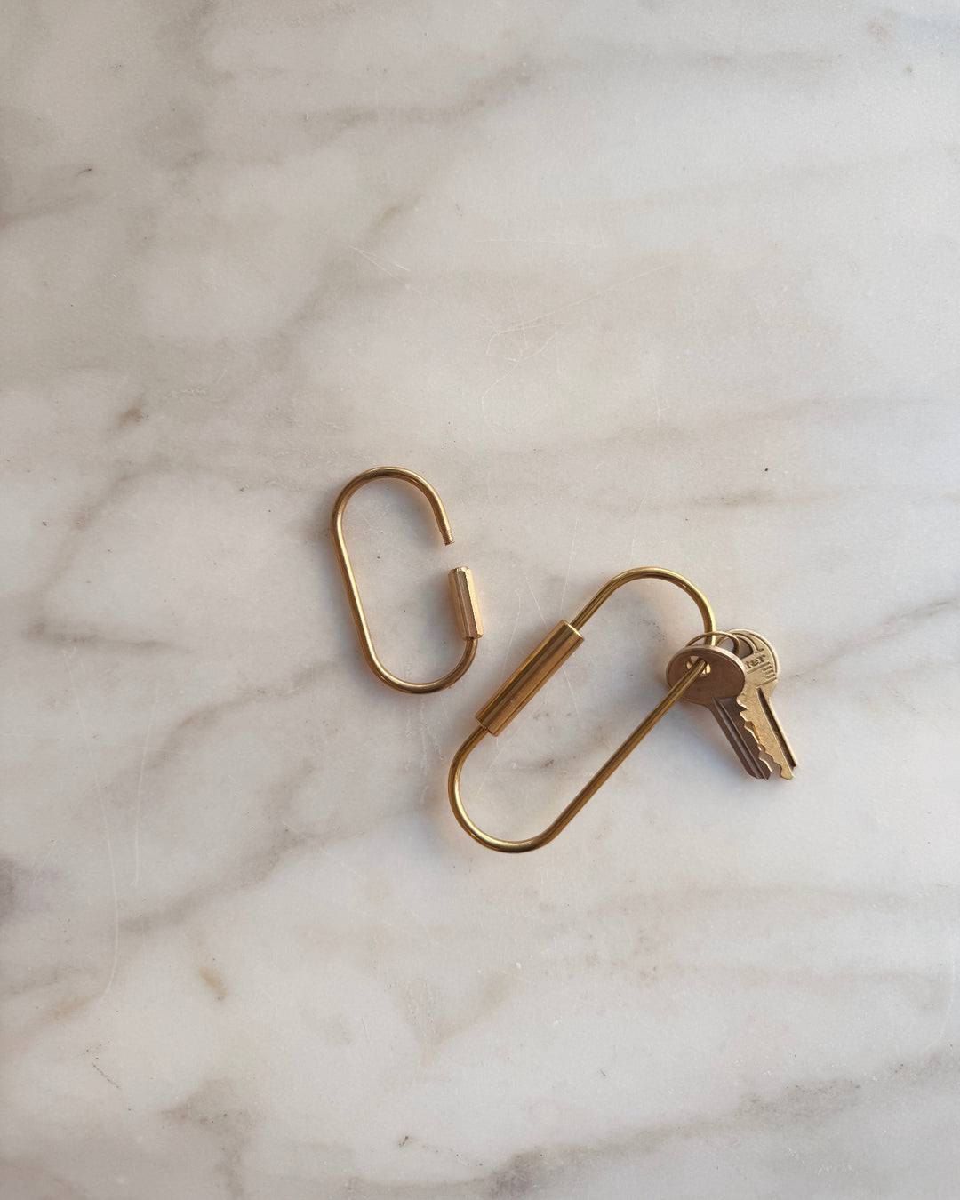 Brass screw lock keychain with a key on a marble surface
