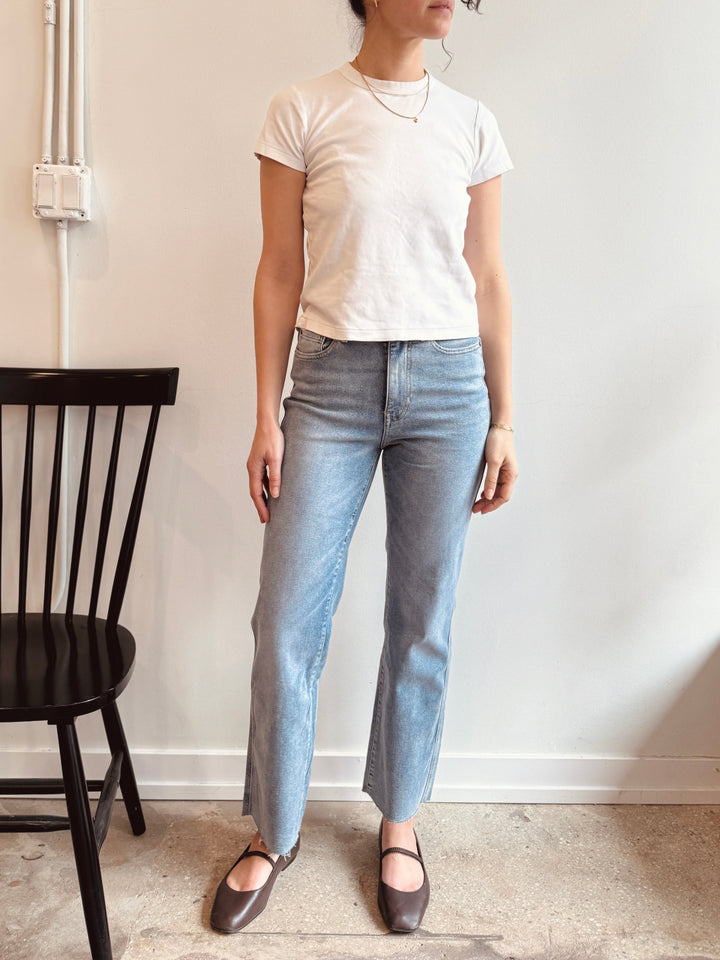 person wearing light blue jeans against a white wall. Winsome chicago cute boutique warp and weft jeans