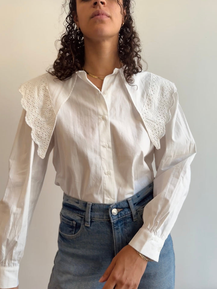 A white cotton button down shirt with exaggerated collars that extend downward.