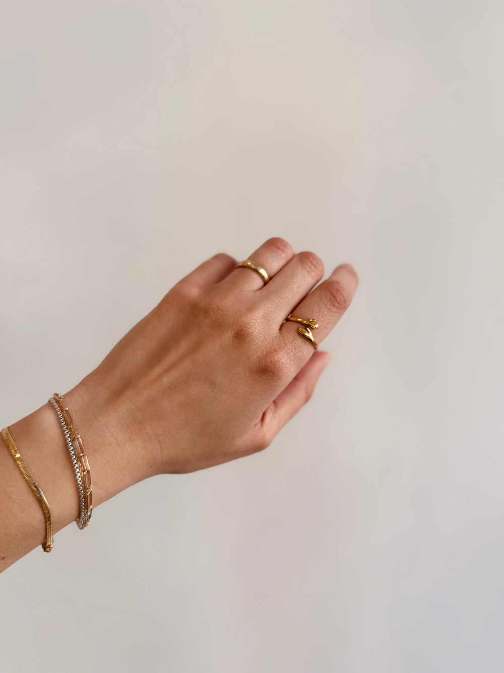 Hand wearing gold hug shaped ring on a plain background from cute chicago boutique winsome clothing and goods