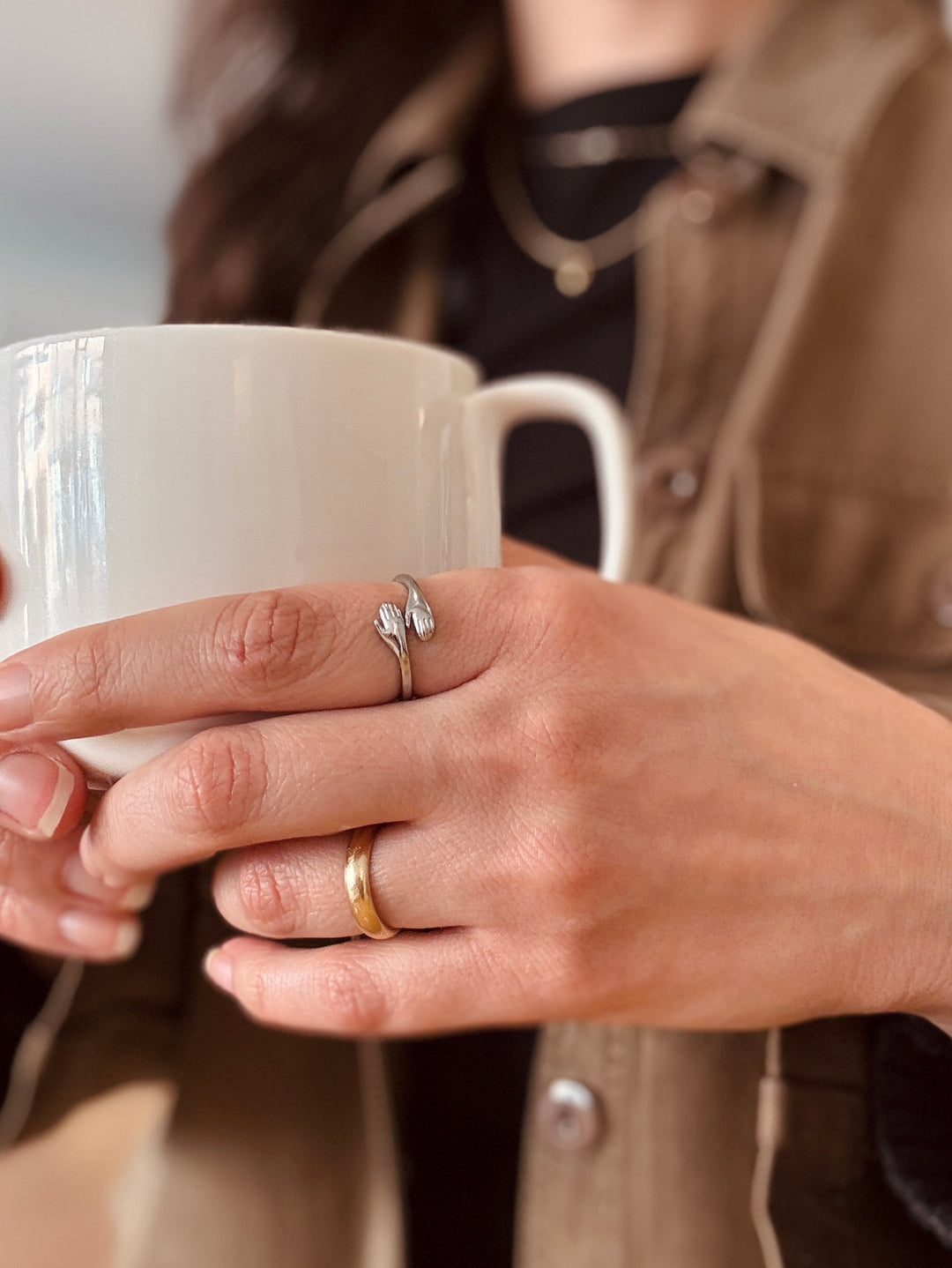 hand holding a small coffee cup wearing a silver hug shaped ring from cute boutique winsome clothing & goods chicago avondale