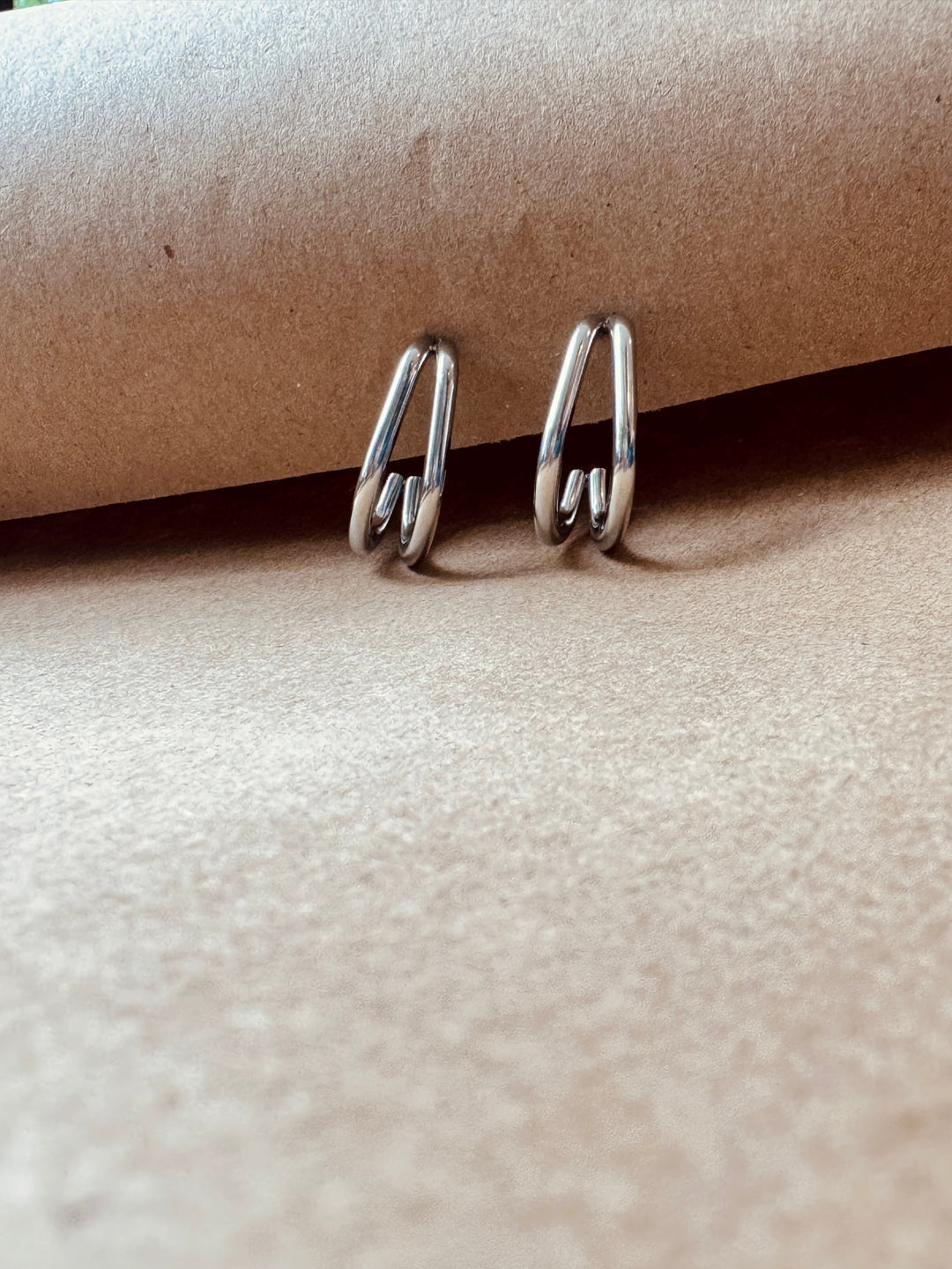 Silver hoop earrings on a textured beige surface