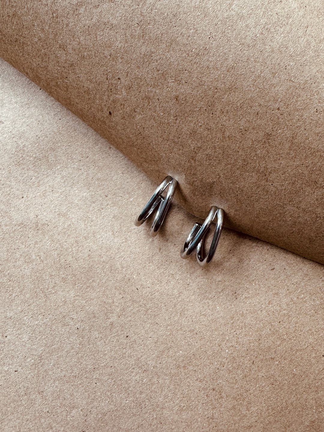 Pair of silver earrings on a beige surface