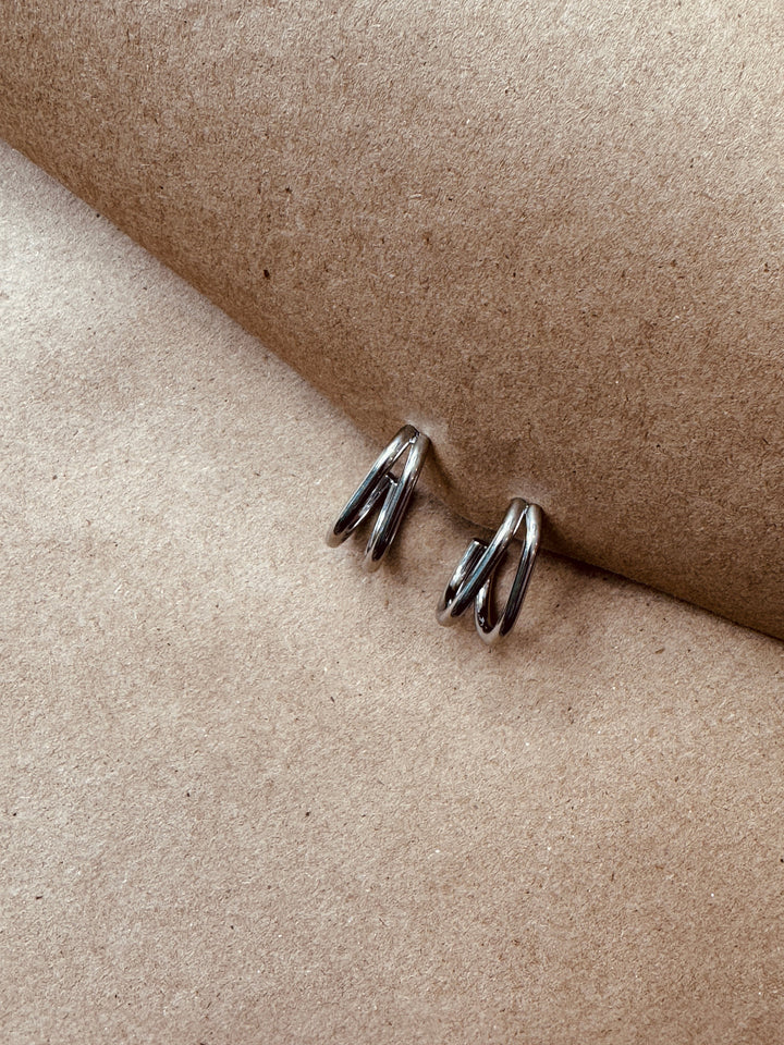 Pair of silver earrings on a beige surface